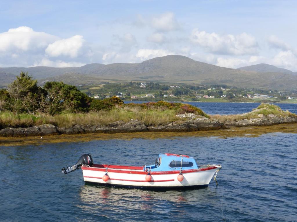a small boat sitting on the water with mountains in the background at Oakfield in Kenmare