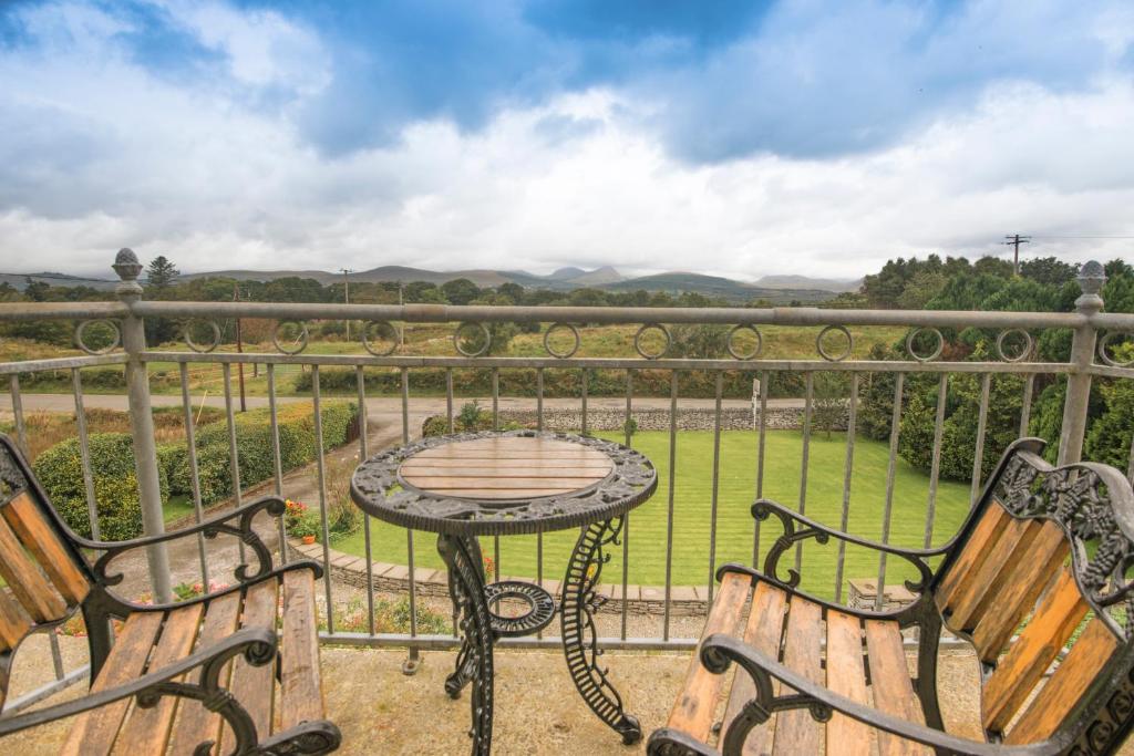 a patio with two benches and a table on a balcony at Oakfield in Kenmare