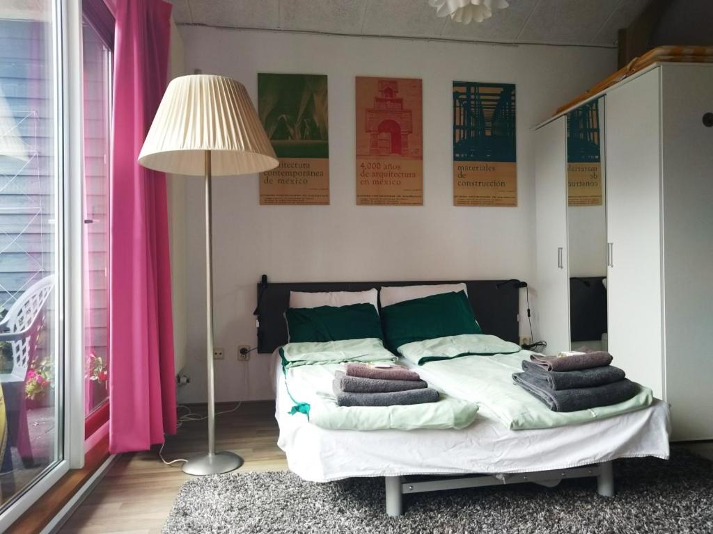 een slaapkamer met een bed met groene kussens en een lamp bij B&B 16C Maassluis NL in Maassluis