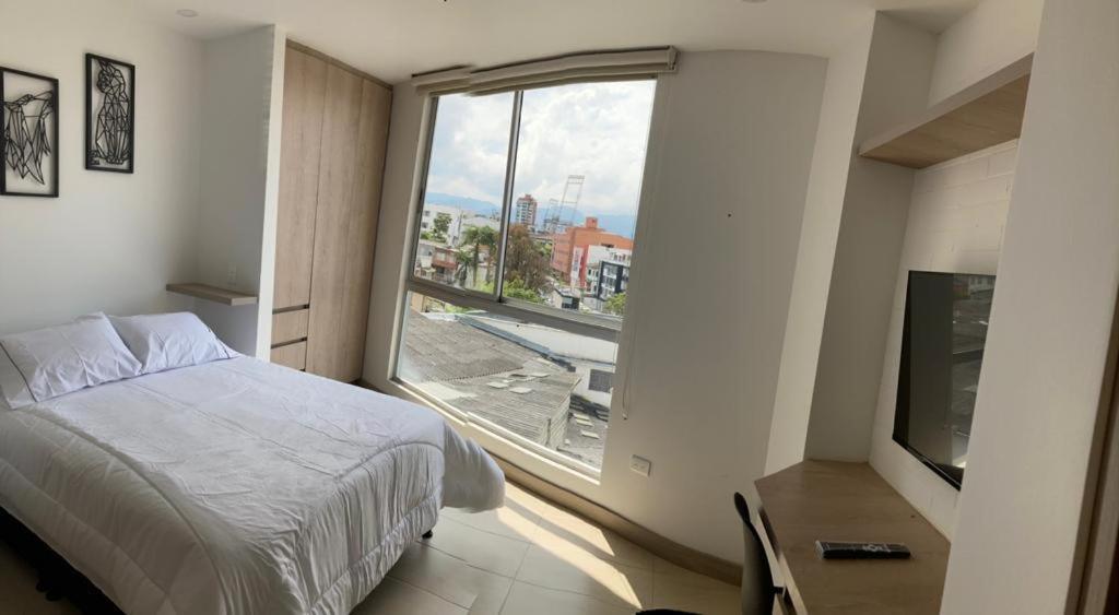 ein Schlafzimmer mit einem Bett und einem großen Fenster in der Unterkunft Apartamento de lujo Manizales in Manizales