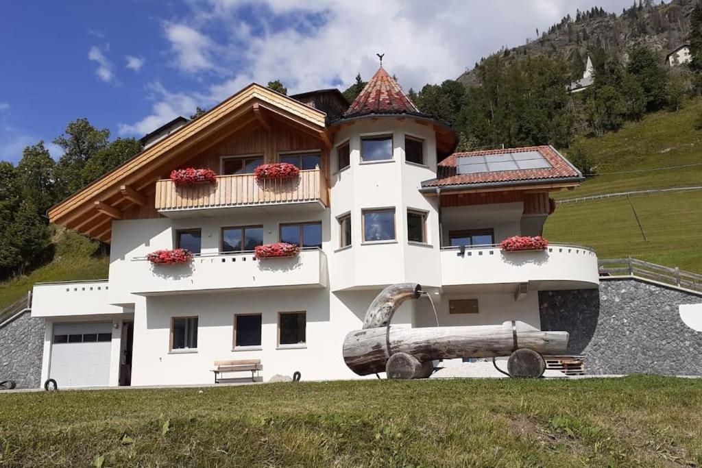 une maison avec un grand rondins devant elle dans l'établissement Appartamento l’ Aier - Arabba - Dolomiti, à Livinallongo del Col di Lana