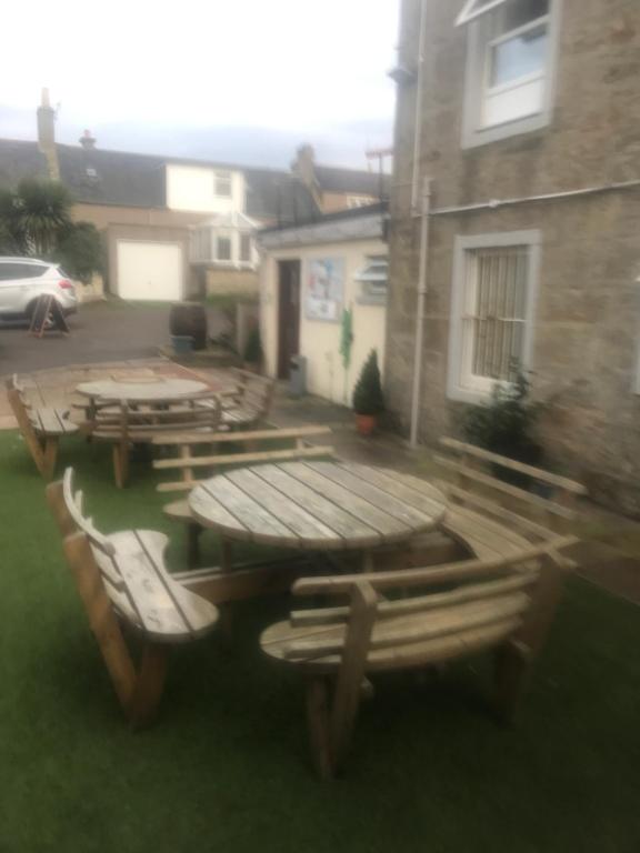 a group of picnic tables and chairs outside a building at Lovely 1-Bed Cottage in Hopeman in Elgin