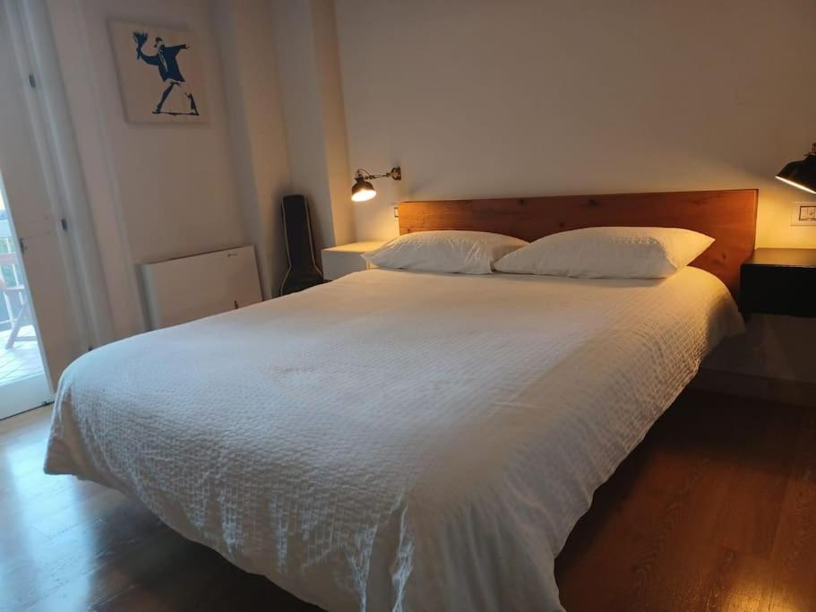1 dormitorio con 1 cama grande con sábanas y almohadas blancas en MiraCapri Home - the strategic centre between Napoli and Sorrento, en Torre del Greco