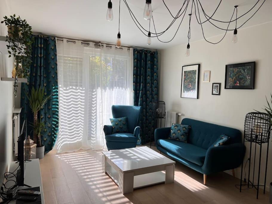 een woonkamer met twee blauwe stoelen en een tafel bij Superbe Appartement 3 pièces près de la Défense in Nanterre