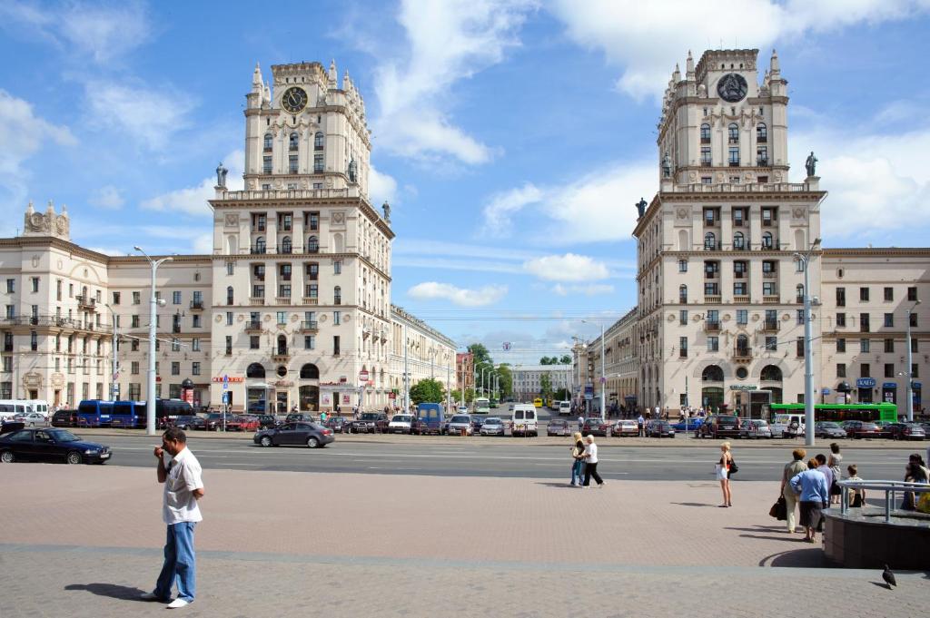 un grupo de personas parados frente a dos grandes edificios en Hostel Platskart, en Minsk
