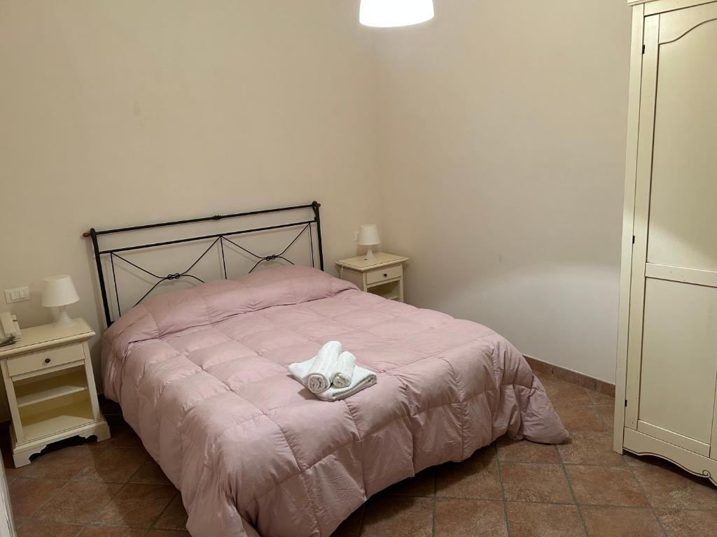 um quarto com uma cama cor-de-rosa com duas mesas-de-cabeceira em Case Vacanza Santoro em Custonaci
