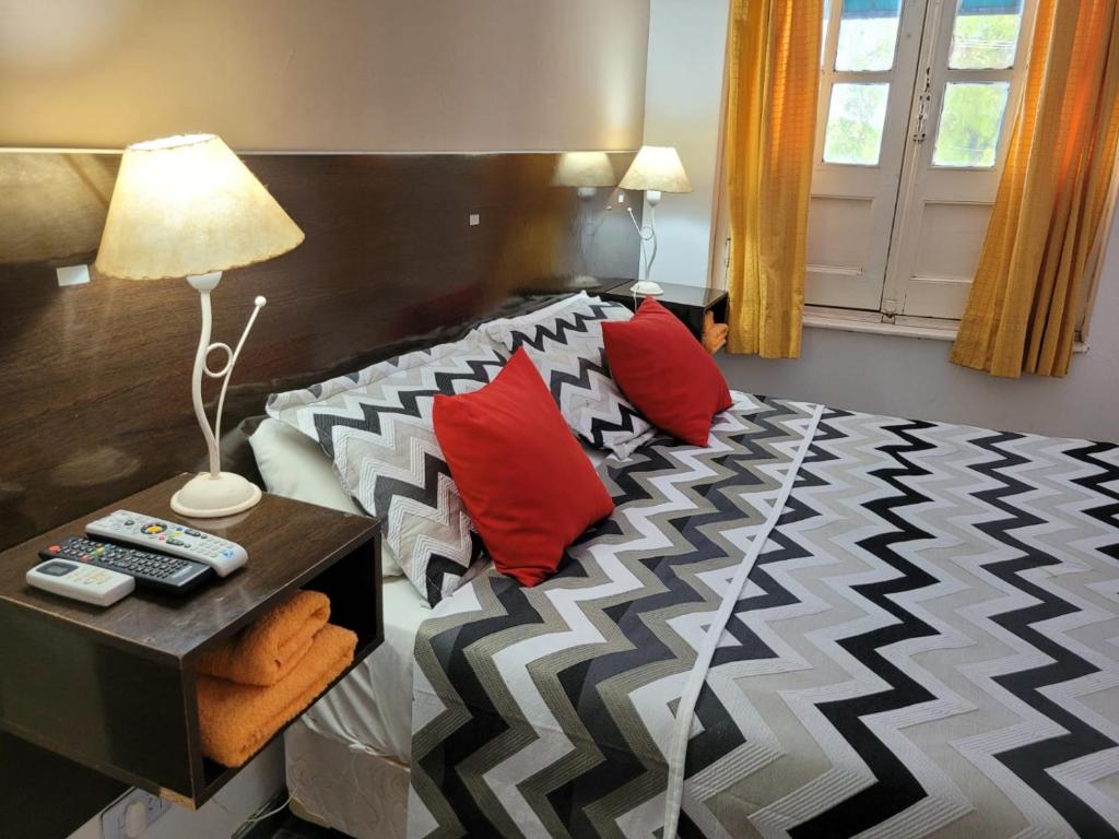 a bedroom with a bed with red pillows and a table at Hotel Uritorco in Capilla del Monte