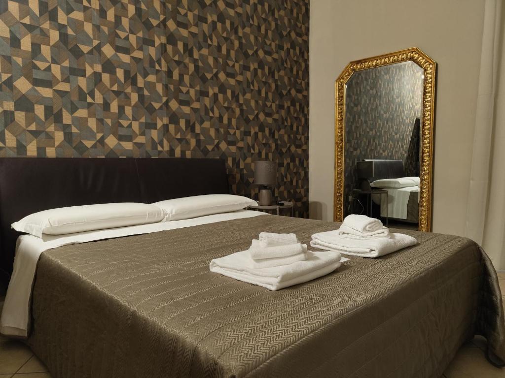 una camera con letto, specchio e asciugamani di Hotel Trieste a Catania