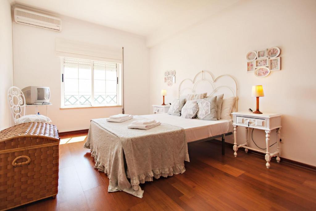 a white bedroom with a large bed and a window at Apartamento Maresia in Faro