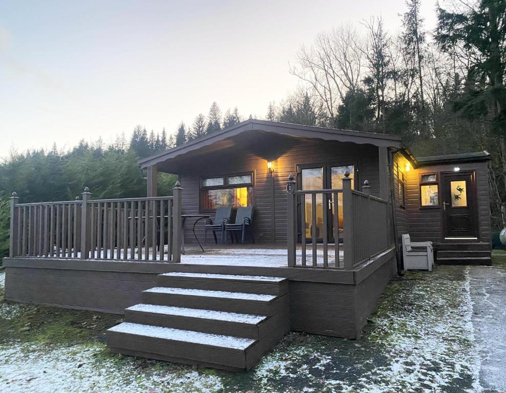 a small cabin with a porch and a deck at Stunning 4-bedroom Cabin with Hot Tub in Beattock! in Beattock