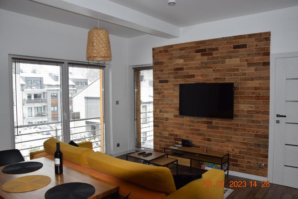 uma sala de estar com um sofá amarelo e uma parede de tijolos em Apartament Spokojny em Wisla
