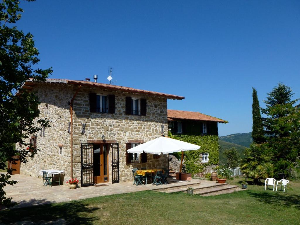 a stone house with a table and an umbrella at Il canto dell'asino in Gubbio