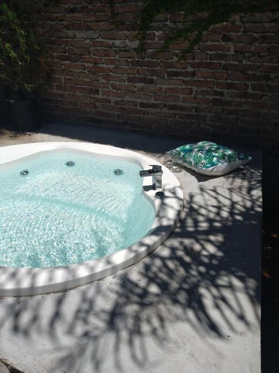 un jacuzzi en un patio trasero con una pared de ladrillo en Casona alegre con jacuzzi en Luján. Argentina en Luján