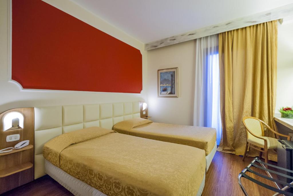 una camera d'albergo con 2 letti e una scrivania di Hotel Delta Florence a Calenzano