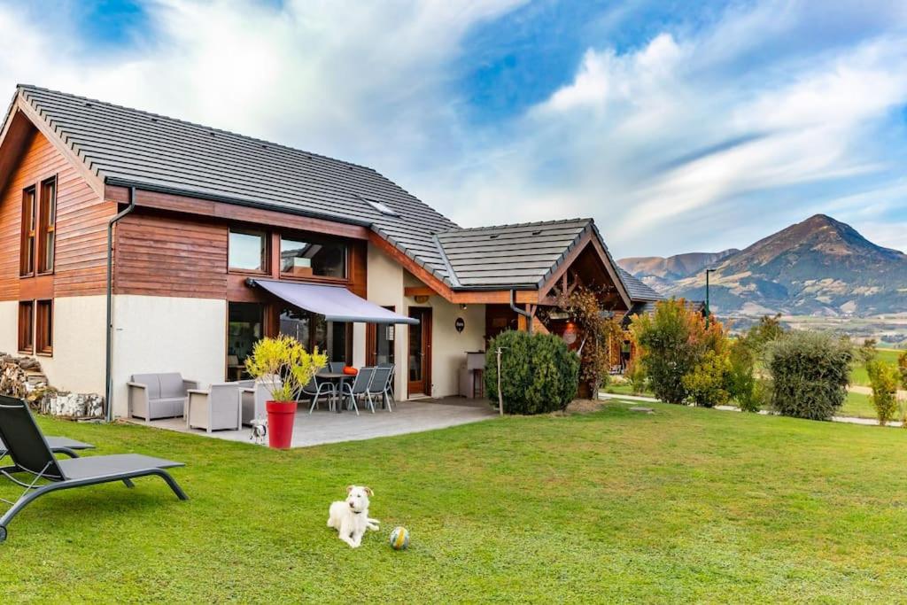 dom z psem siedzącym na podwórku w obiekcie Maison dans les Alpes - Gîte les 12 sommets w mieście Ponsonnas