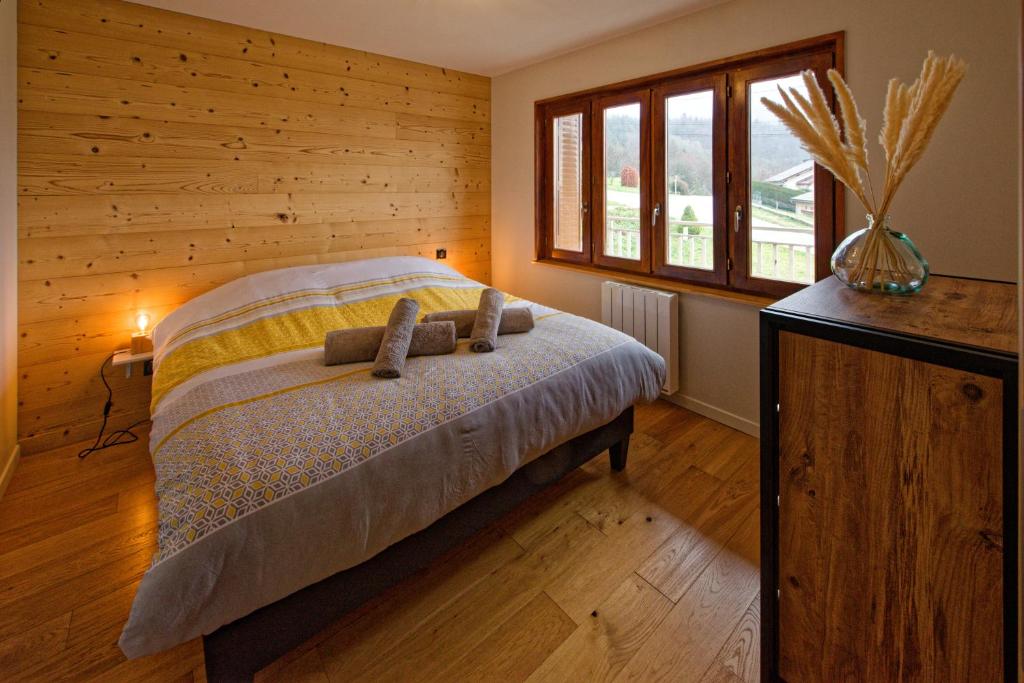a bedroom with a bed with a wooden wall at Cocon d'hiver dans le Jura - Option spa - Gîte cosy chez Ô JurassiK in Cuttura