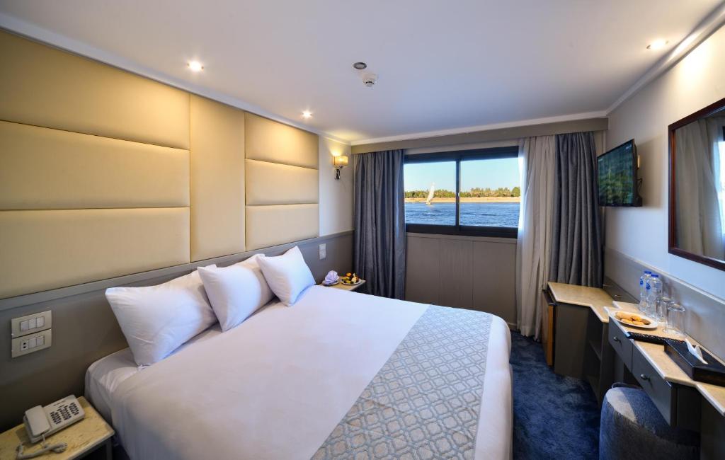 ein Hotelzimmer mit einem großen Bett und einem Fenster in der Unterkunft Nile Treasure Cruise - 4 or 7 Nights From Luxor each Saturday and 3 or 7 Nights From Aswan each Wednesday in Luxor