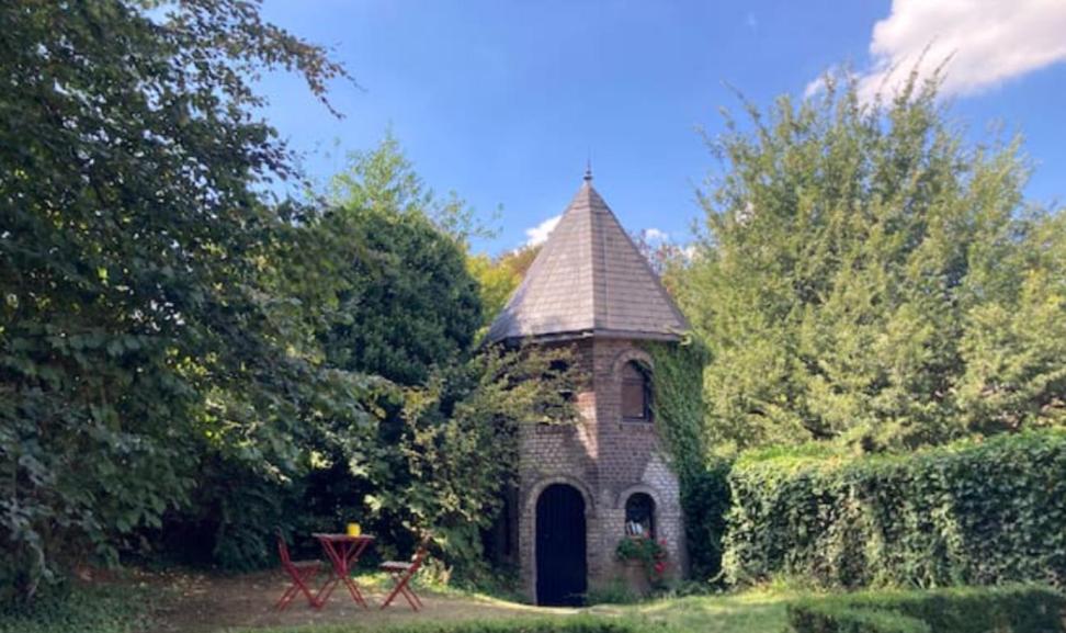 un petit bâtiment en briques avec une tour dans un jardin dans l'établissement Le pigeonnier - TinyHouse en plein centre de Liège, à Liège