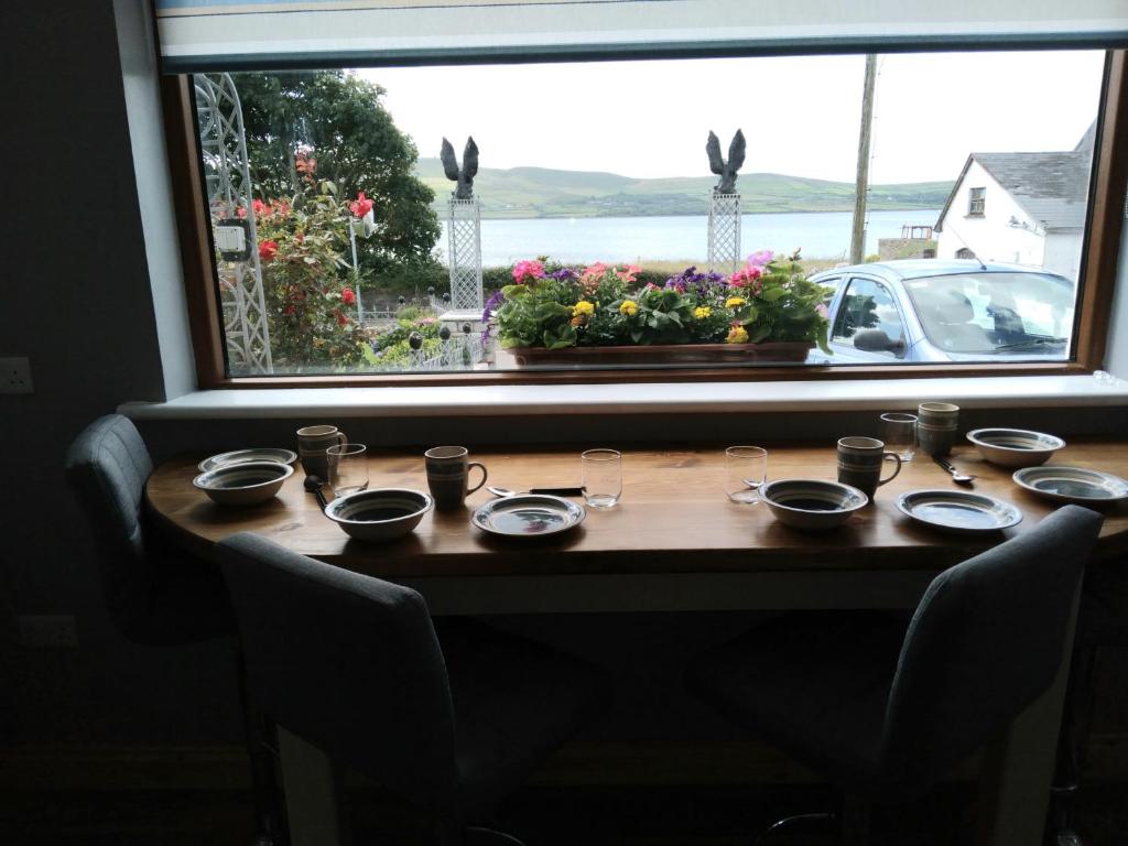 une table avec des assiettes et des verres devant une fenêtre dans l'établissement The Dingle Galley, à Dingle