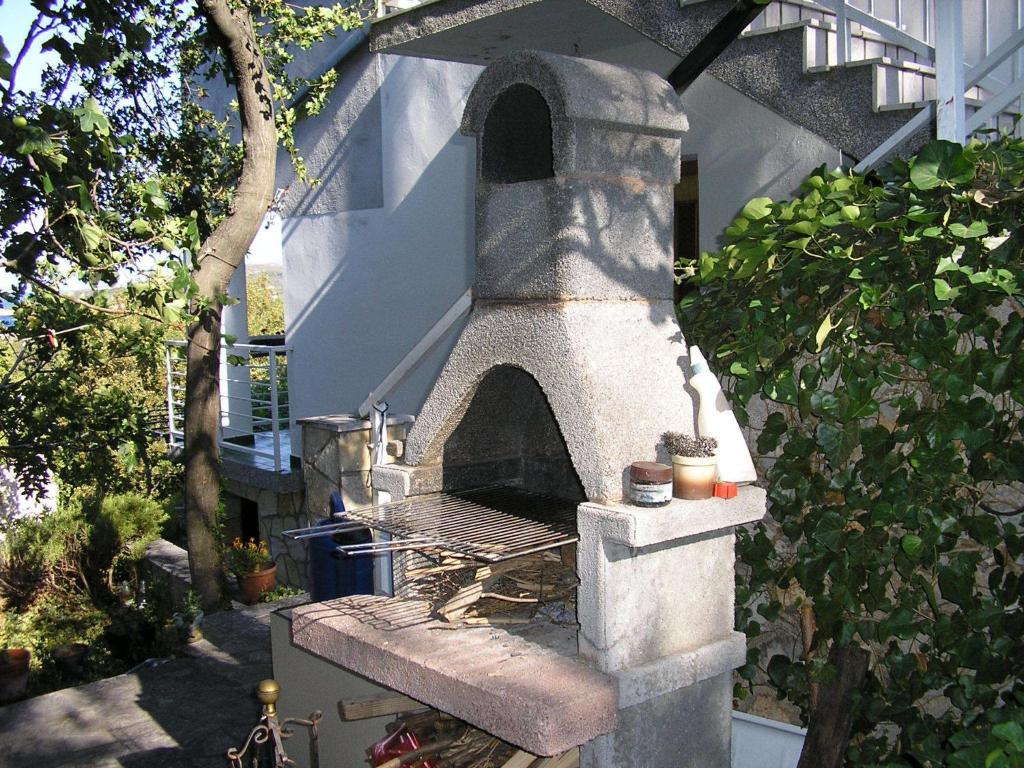 un horno de pizza de piedra sentado en un lado de una casa en Apartment Bilić, en Klenovica
