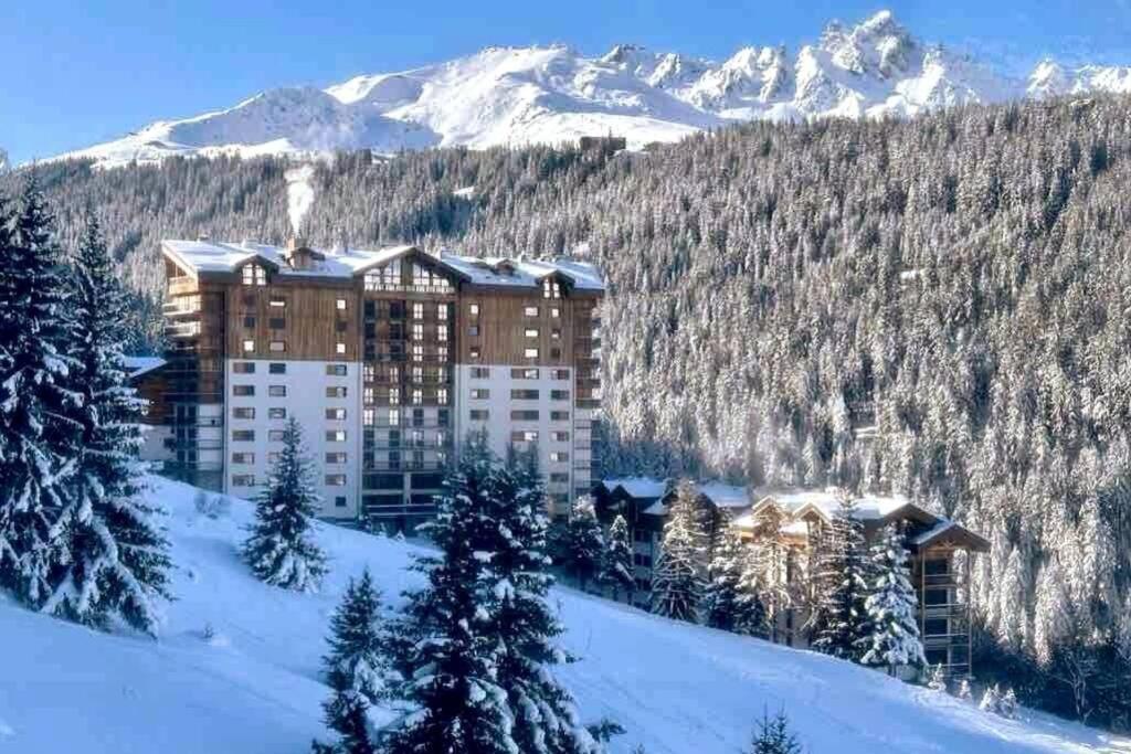 a hotel in the snow with mountains in the background at T3 neuf Courchevel 1650 Domaine de l’Ariondaz in Courchevel