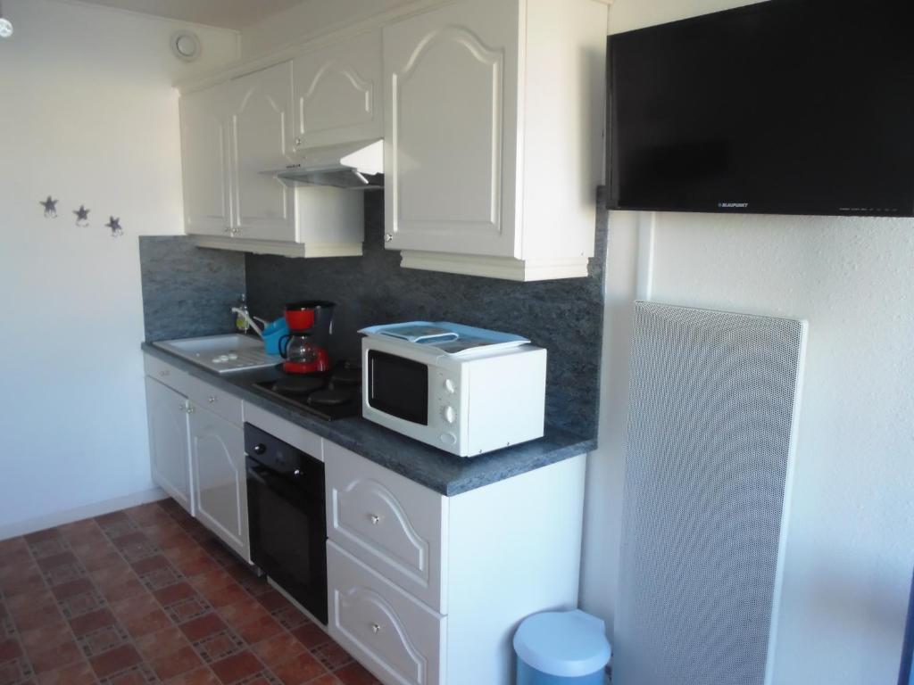 a small kitchen with white cabinets and a microwave at Vue Mer 180° Parking+Lave-Linge+Proche Plages+Piscine in Cap d&#39;Agde