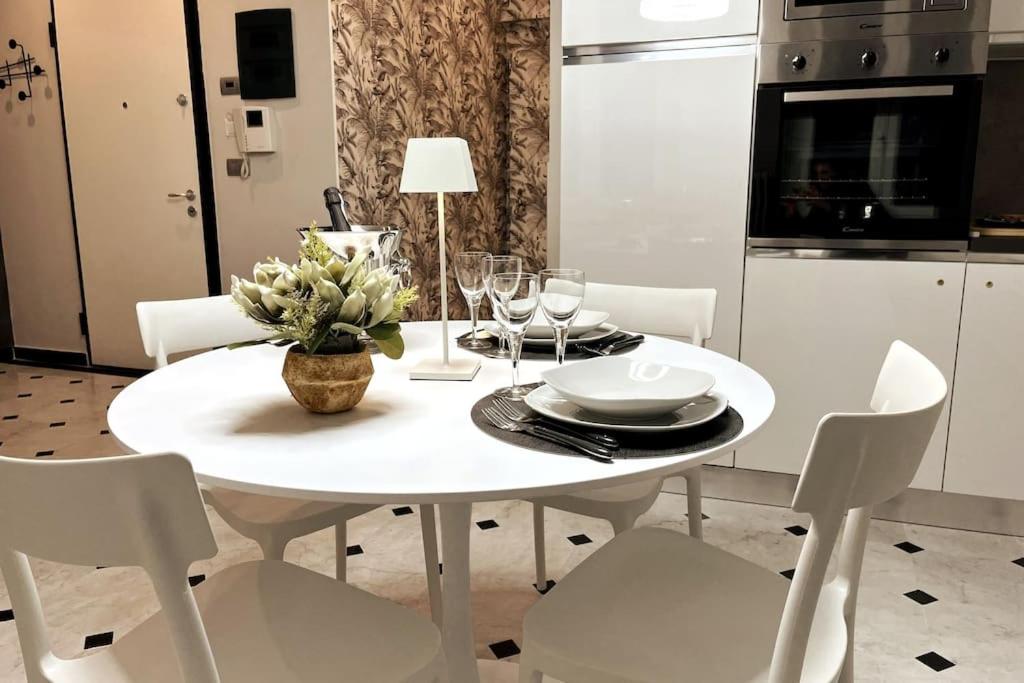 a white dining room table with white chairs and a table with a bowl at Vico Stella Luxury Apartment, Centro storico, Porto Antico Acquario in Genova