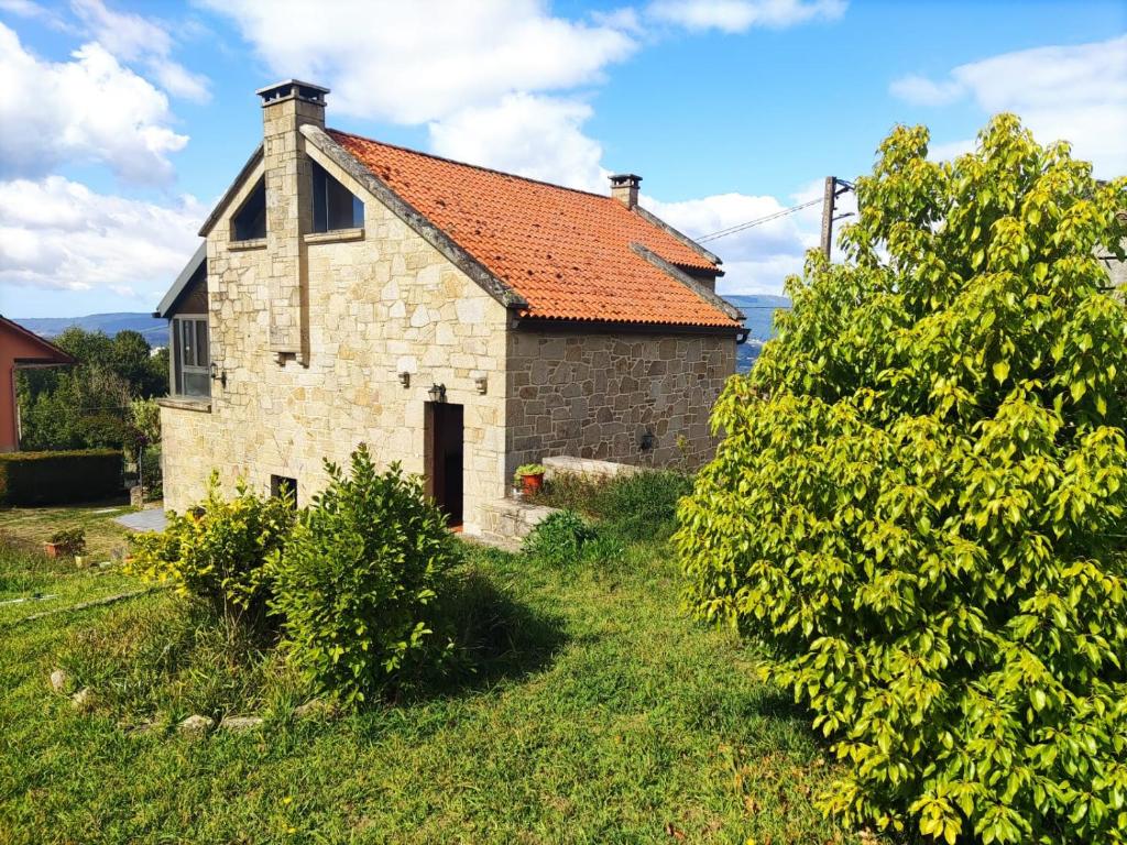 une ancienne maison en pierre avec un toit rouge dans l'établissement Casa con encanto en el campo, à Pontevedra