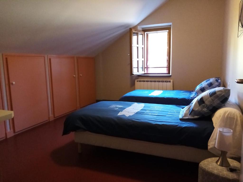a bedroom with two beds and a window at Auberge du Marronnier in Belmont-sur-Rance