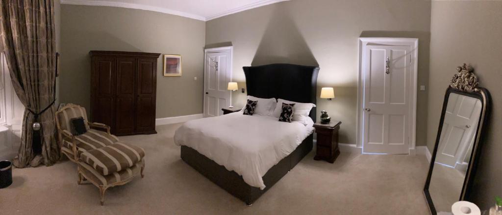 um quarto com uma cama grande e uma cadeira em West End Townhouse em Edimburgo