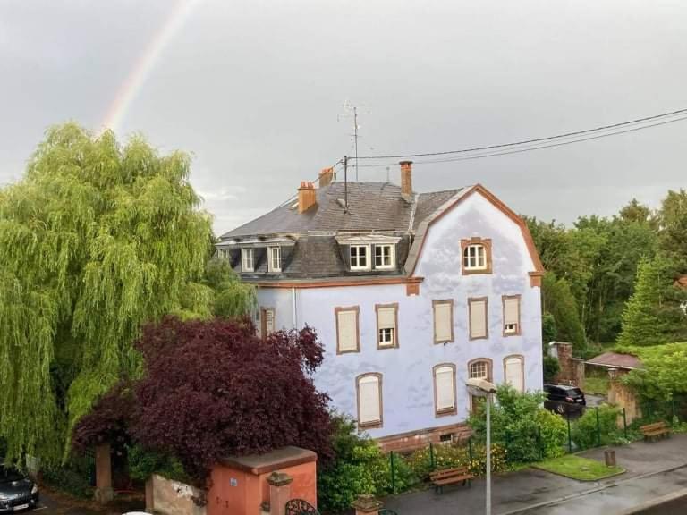 une grande maison blanche avec un arc-en-ciel en arrière-plan dans l'établissement Le tribunal alsacien, à Bouxwiller