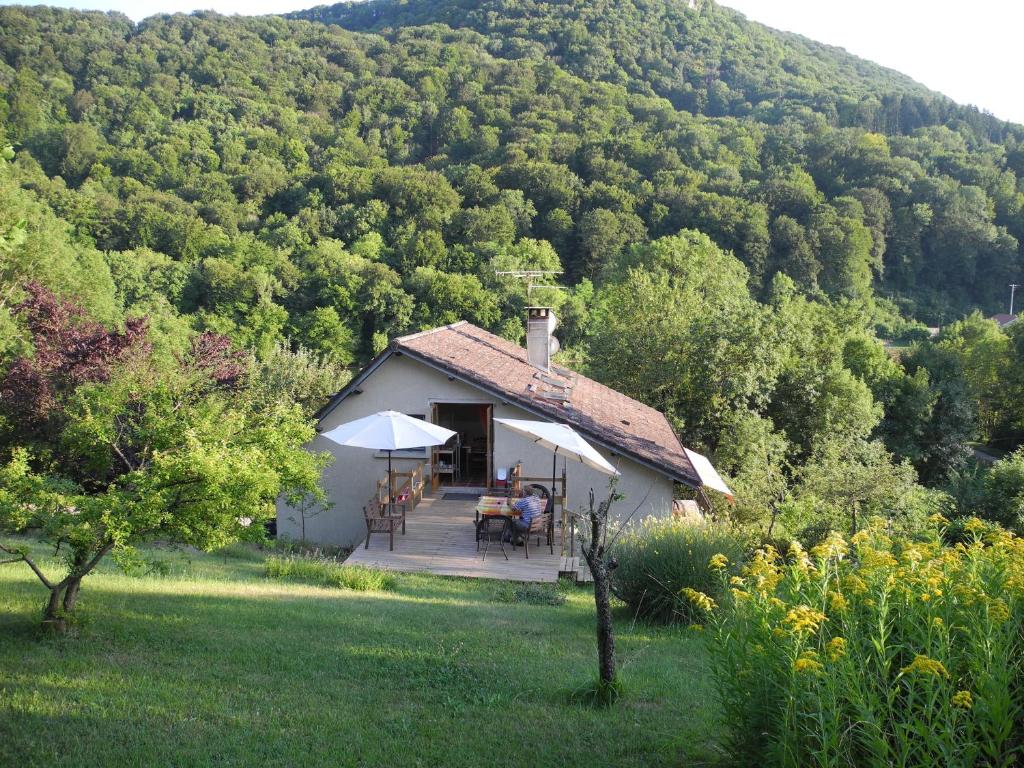 a small cottage with a table and chairs in front of a mountain at La Maison Imparfaite in Fourbanne