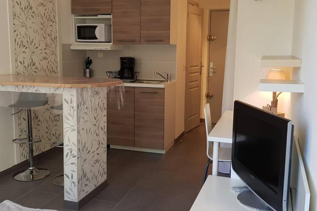 a kitchen with a table and a tv in a room at COSY FLAT in Bussy-Saint-Georges