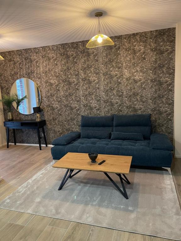 ein Wohnzimmer mit einem blauen Sofa und einem Tisch in der Unterkunft Appartement Jungle centre confort et spacieux netflix wifi gratuit in Saint-Étienne