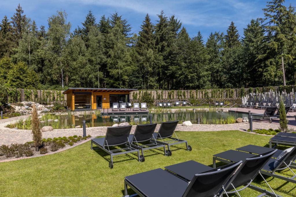 einen Hinterhof mit Stühlen und einem Teich und einer Hütte in der Unterkunft Hotel Heidegrund in Petersfeld