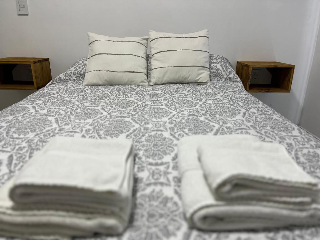 Una cama con almohadas y toallas encima. en Departamento Hilario en San Rafael