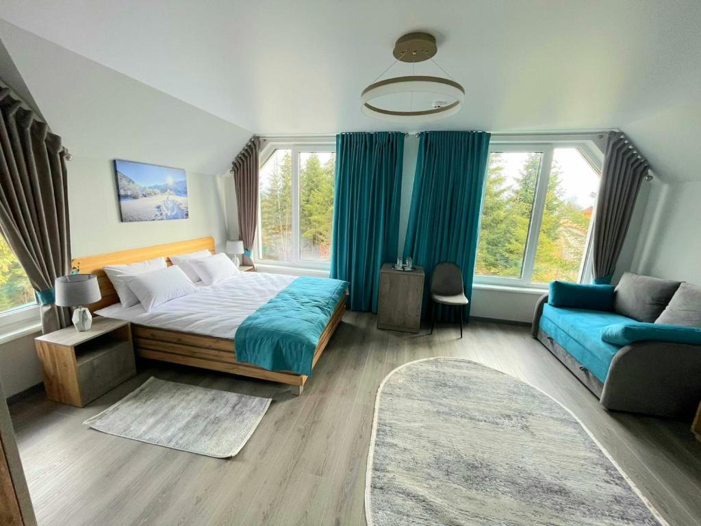 a bedroom with a large bed and a blue couch at Отель MONBLAN in Yablunytsya