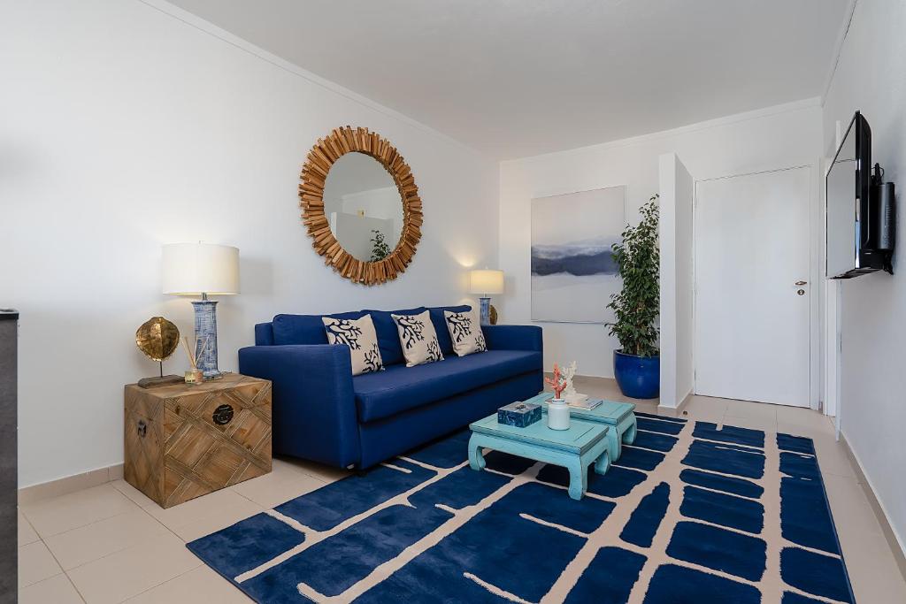 ein Wohnzimmer mit einem blauen Sofa und einem Tisch in der Unterkunft Bianca Rocha in Portimão