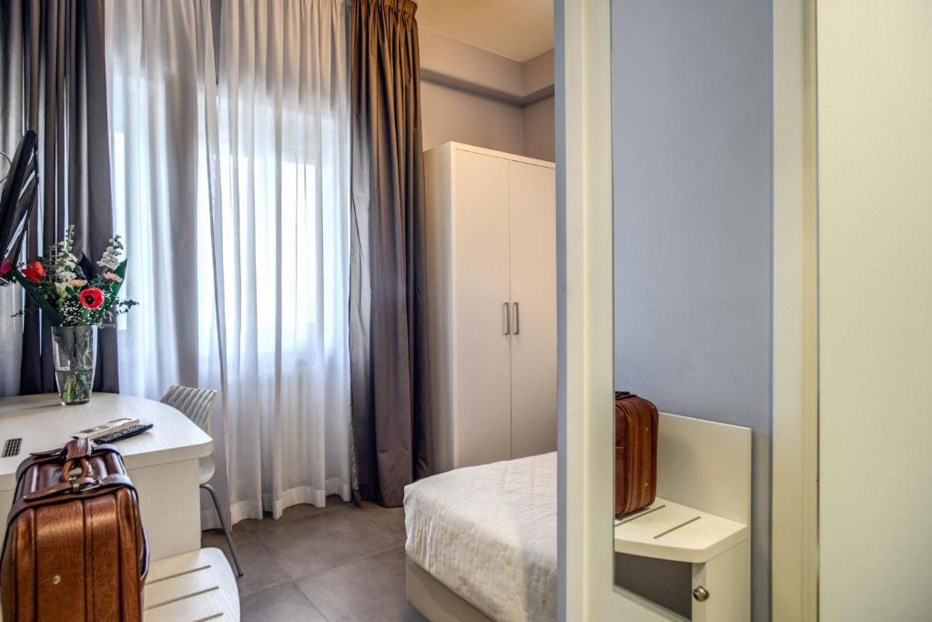 ローマにあるCasa per Ferie Ravasco San Pietroのベッド、デスク、窓が備わる客室です。