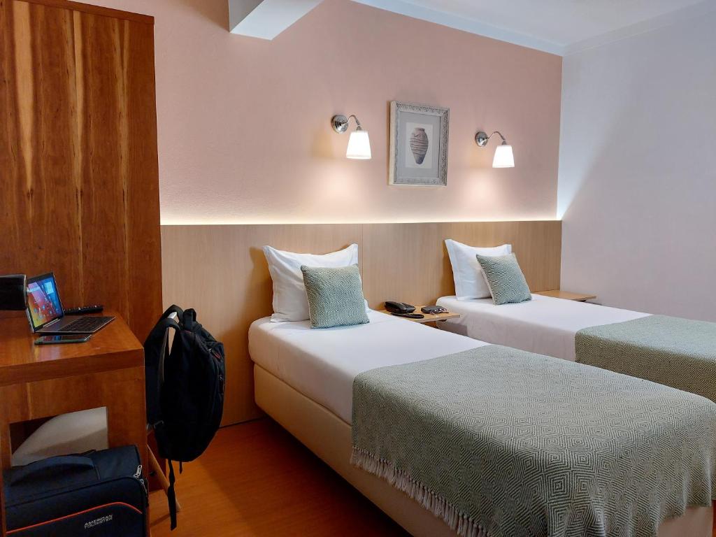 a hotel room with two beds and a desk at Hotel Santiago in Ílhavo