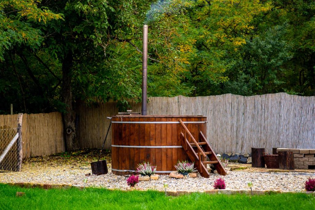 a wooden hot tub in a yard next to a fence at Kata Cottage in Szanda