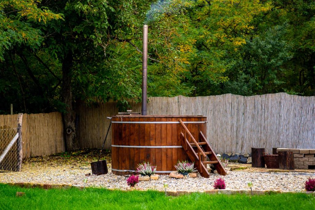 una bañera de hidromasaje de madera en un patio junto a una valla en Kata Cottage, en Szanda