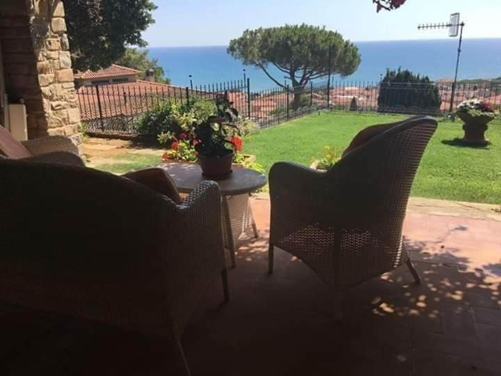 d'une terrasse avec des chaises et une table offrant une vue sur la cour. dans l'établissement APPARTAMENTI PANORAMICI VISTA MARE, à Castiglione della Pescaia
