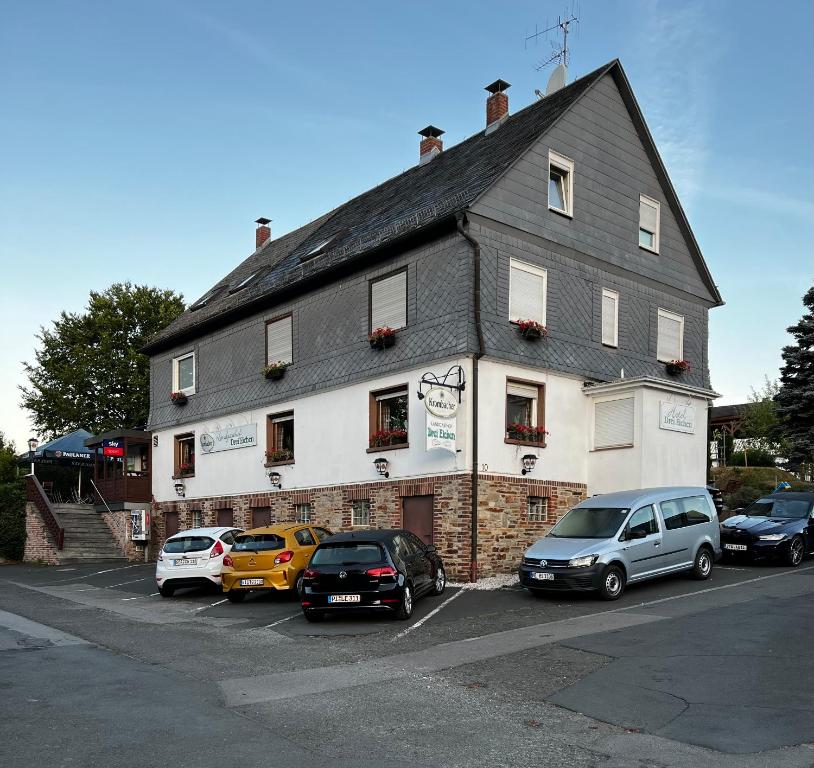 un bâtiment avec des voitures garées devant lui dans l'établissement Landgasthof Drei Eichen, à Wilnsdorf