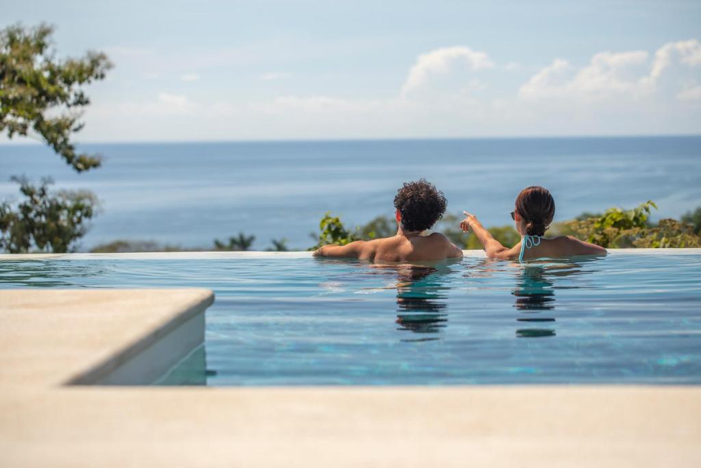 un hombre y una mujer en una piscina en Adeluna Luxury Villas, en Montezuma
