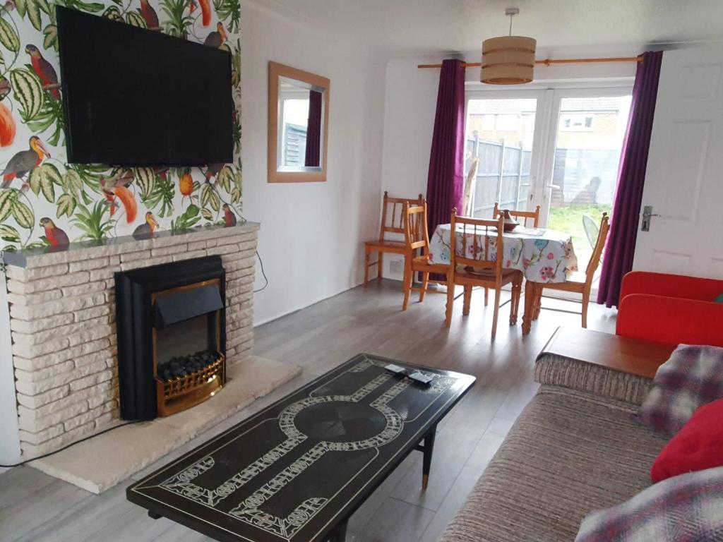a living room with a fireplace and a tv at Owl Haven: Comfortable central 3 bedroom house, with an enclosed garden. in Bicester