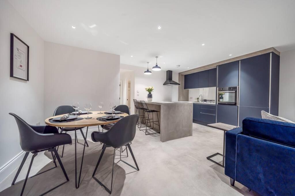 a kitchen and dining room with a table and a blue couch at Trendy 2 bedroom 2 bathroom apartment minutes from seafront in St Leonard's Hastings in St. Leonards