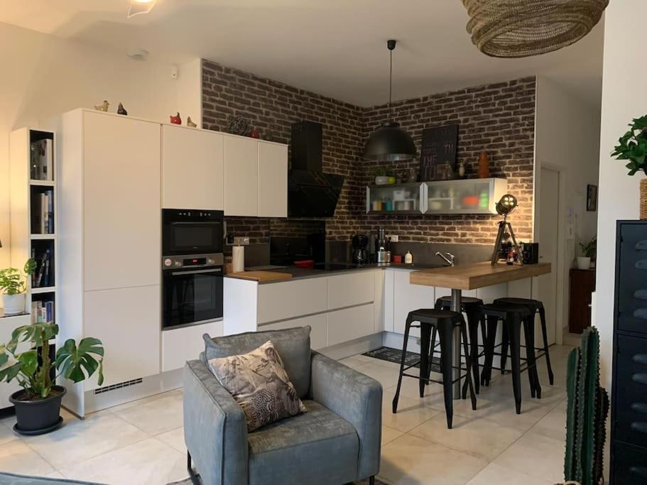 a kitchen with white cabinets and a chair and a table at Logement spacieux tout confort in Pont-à-Mousson