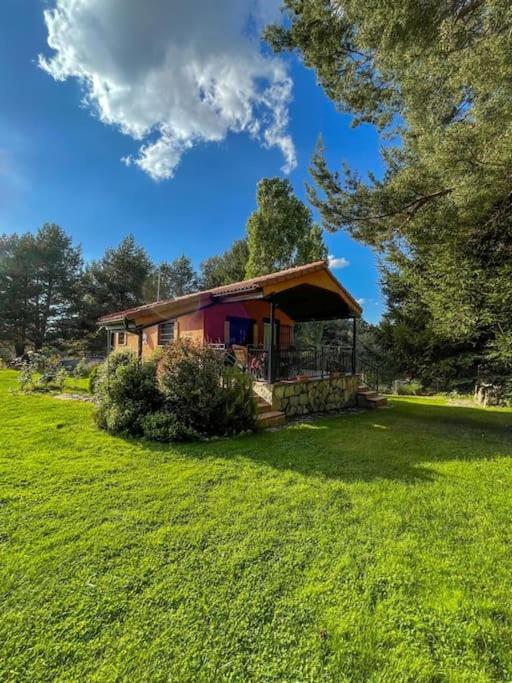 a small house in a grassy field with a tree at La Finca de Gredos in Hoyos del Espino