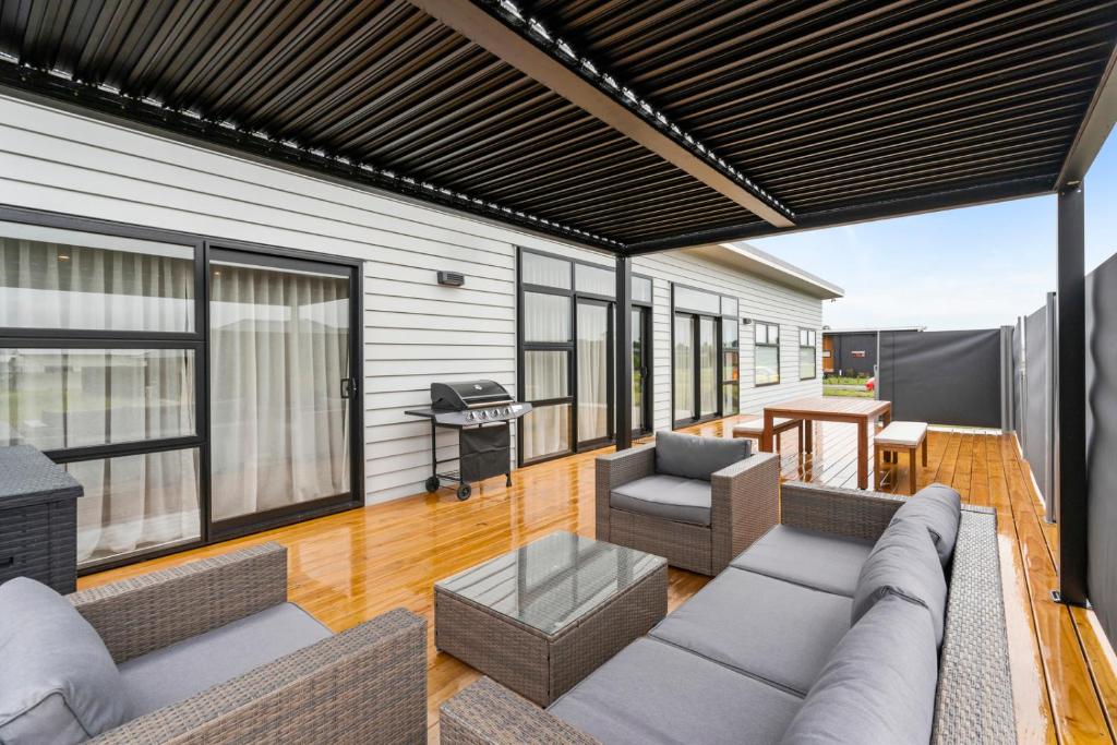 ein Wohnzimmer im Freien mit einem Sofa und Stühlen in der Unterkunft Pride of Pinot - Martinborough Holiday Home in Martinborough 